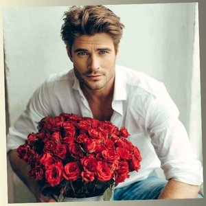 A man holding a bouquet of red roses with a gentle, warm expression