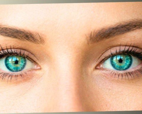 An extreme close-up of a person's vibrant green and turquoise eyes looking directly forward with a focused and slightly self-conscious expression.